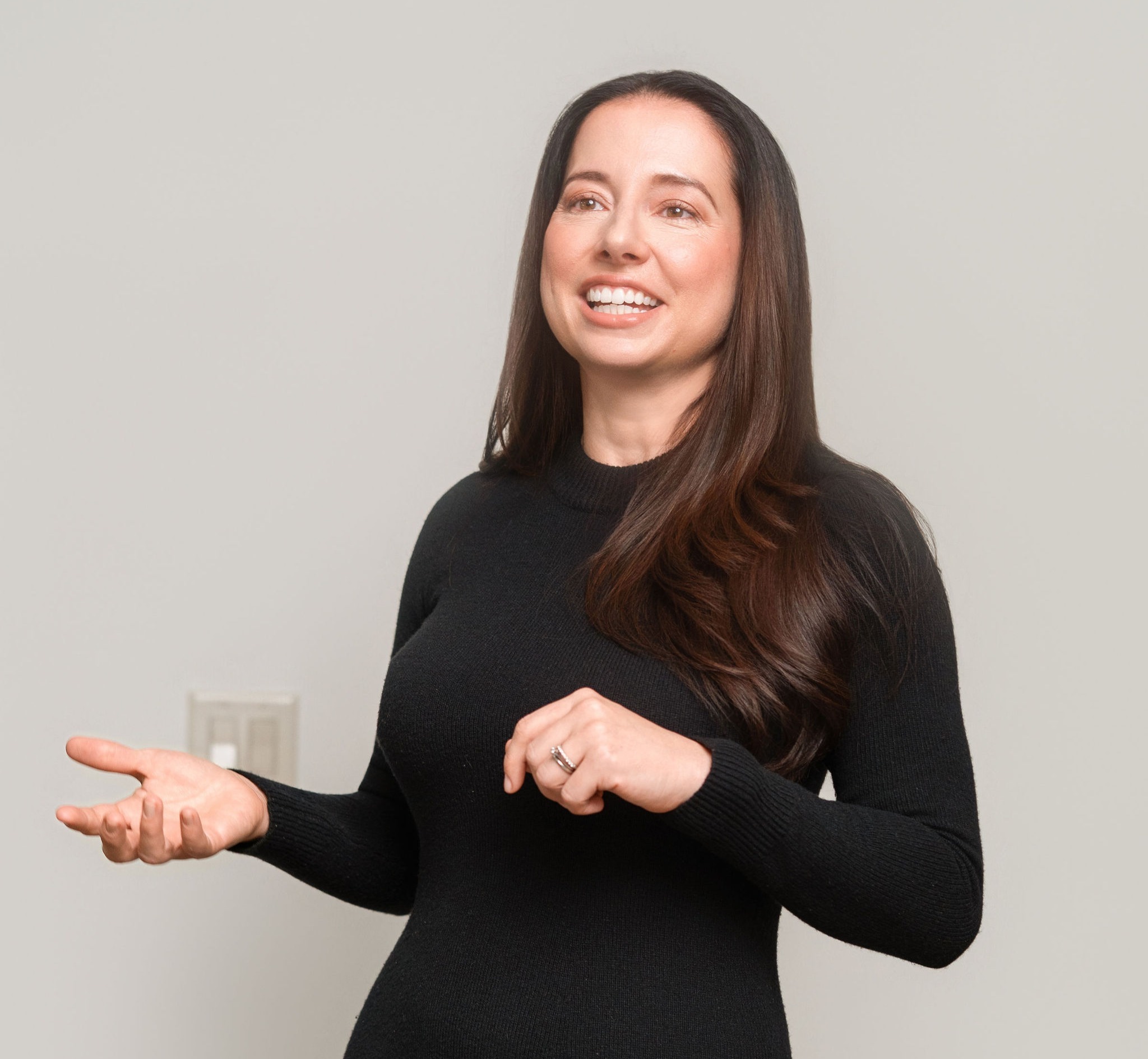 An in-action photograph of Ruthann Savage, Founder of Savage Dynamic Consulting, taken in a neutral setting with soft, natural lighting while presenting compelling information. The founder is smiling confidently, conveying approachability and credibility.